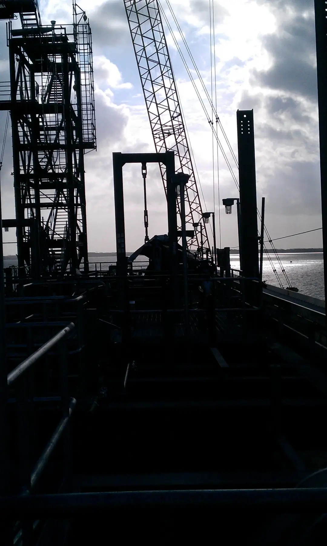 Industrial structural steel and piping at a waterfront facility with crane