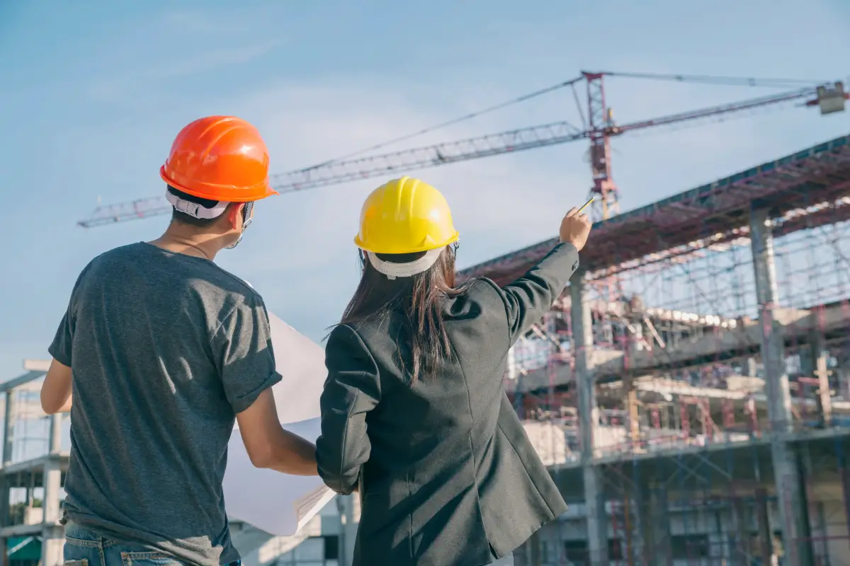 Two engineers in hard hats reviewing a structural project at a construction site